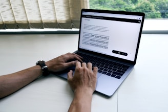 person using macbook pro on white table