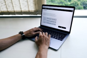A person working on a laptop with a PDF document on the screen.