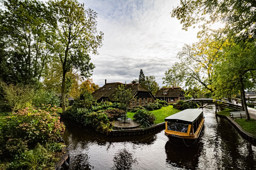 brown boat on river near green trees during daytime