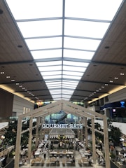 A lively food court with diverse international dishes and a cozy theater stage above.