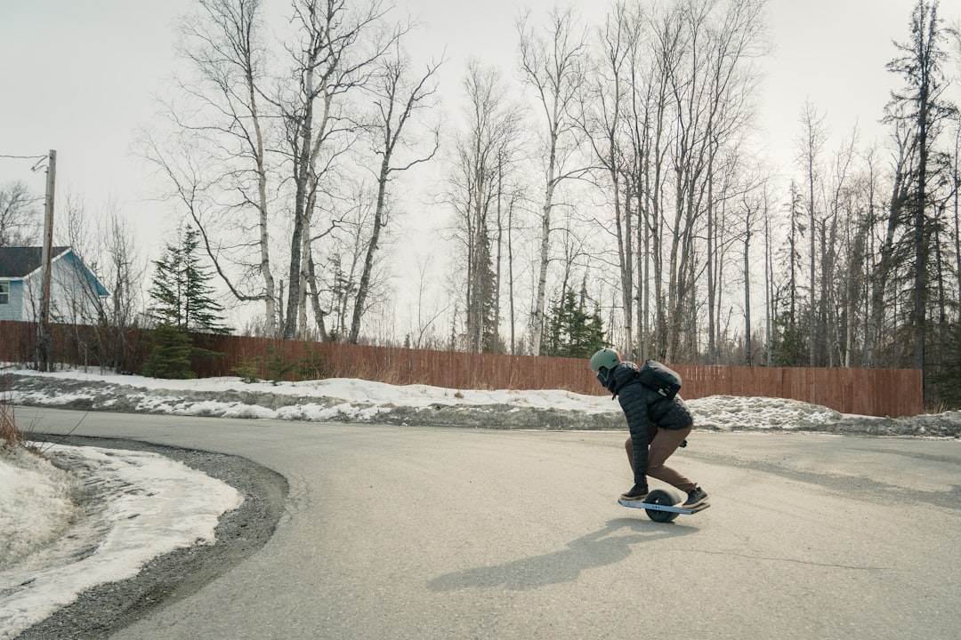 person in black jacket and black pants riding on black skateboard on snow covered ground during