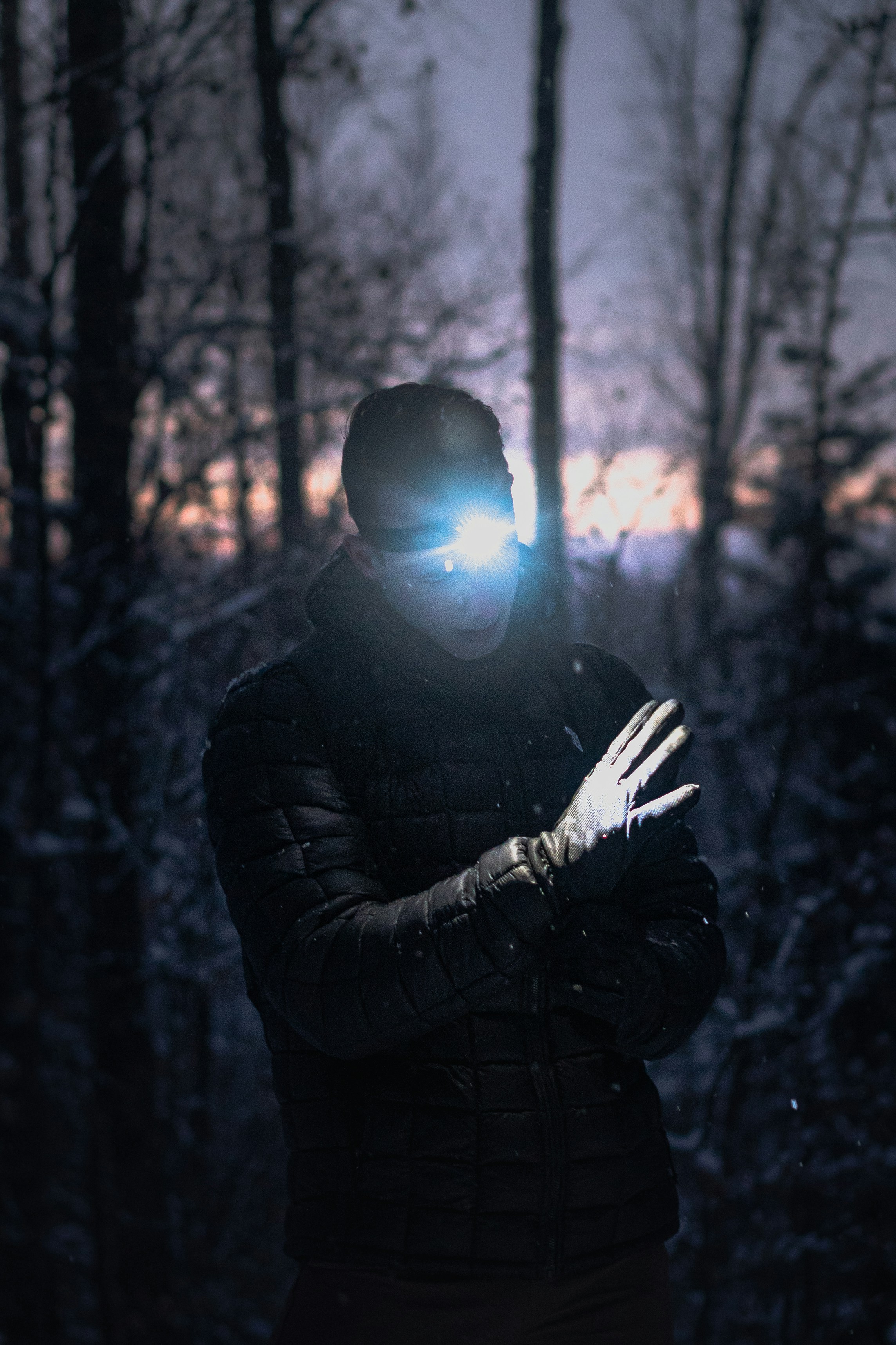 man in black jacket raising his hand in the woods
