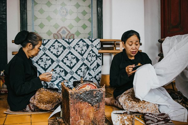 2 women sitting on brown and white floral sofa — Yogyakarta, Indonesia