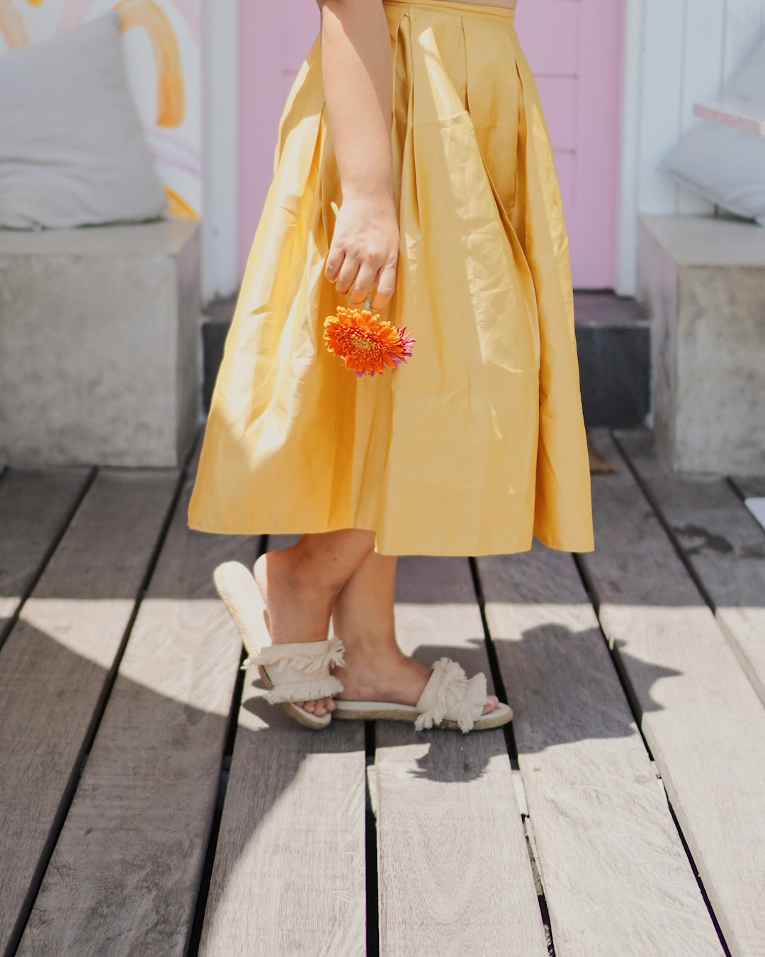 woman in yellow sleeveless dress and white peep toe heeled shoes holding orange flower bouquet