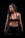 A woman with curly black hair is wearing a dark athletic outfit, including a sports bra and shorts, and holding a kettlebell. The background is completely black, emphasizing her muscular physique.