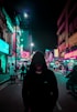 man in black hoodie walking on street during night time