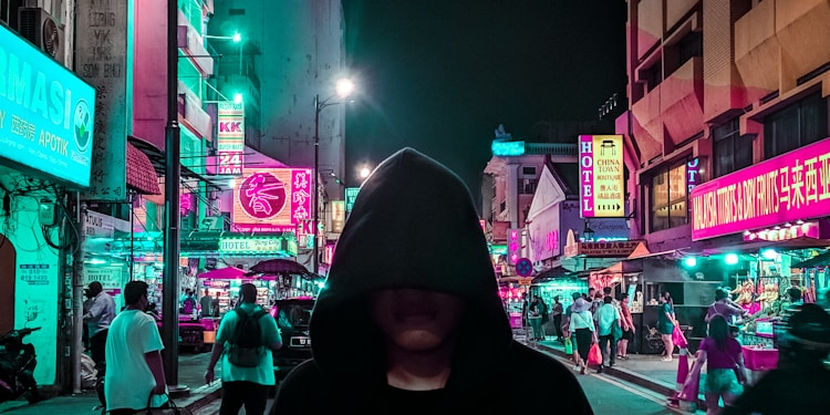 man in black hoodie walking on street during night time