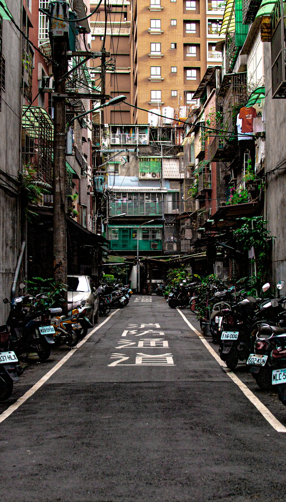 a narrow city street lined with parked motorcycles