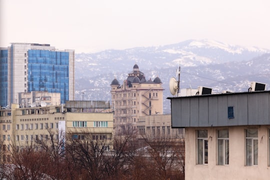 brown concrete building near trees during daytime in Almaty Kazakhstan