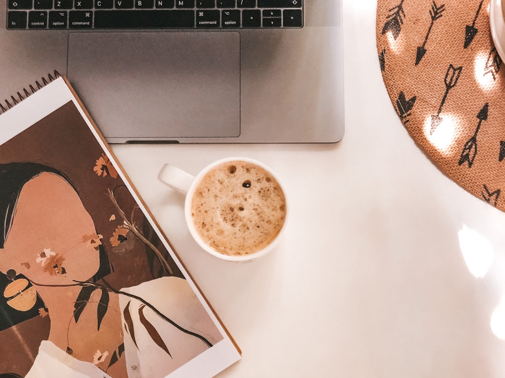 white ceramic mug beside silver macbook