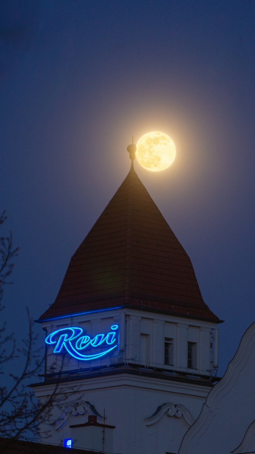 Una luna piena sorge su un edificio con una torre dell'orologio
