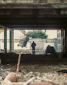 man in black jacket standing near brown wooden post during daytime