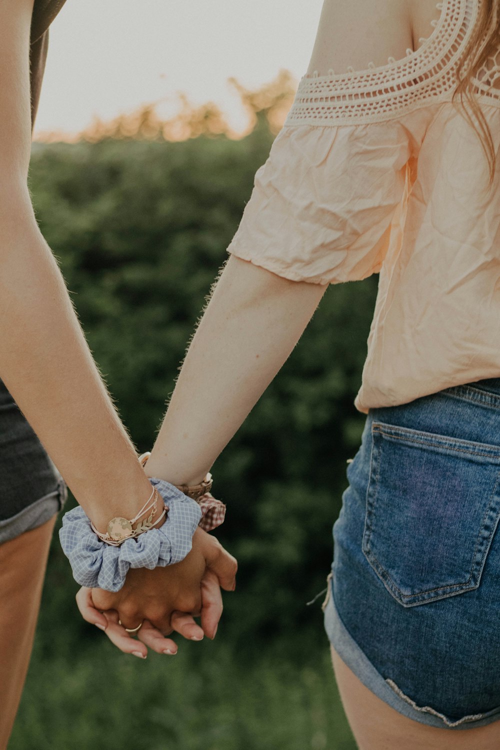 woman in white shirt and blue denim jeans holding hands with woman in white shirt