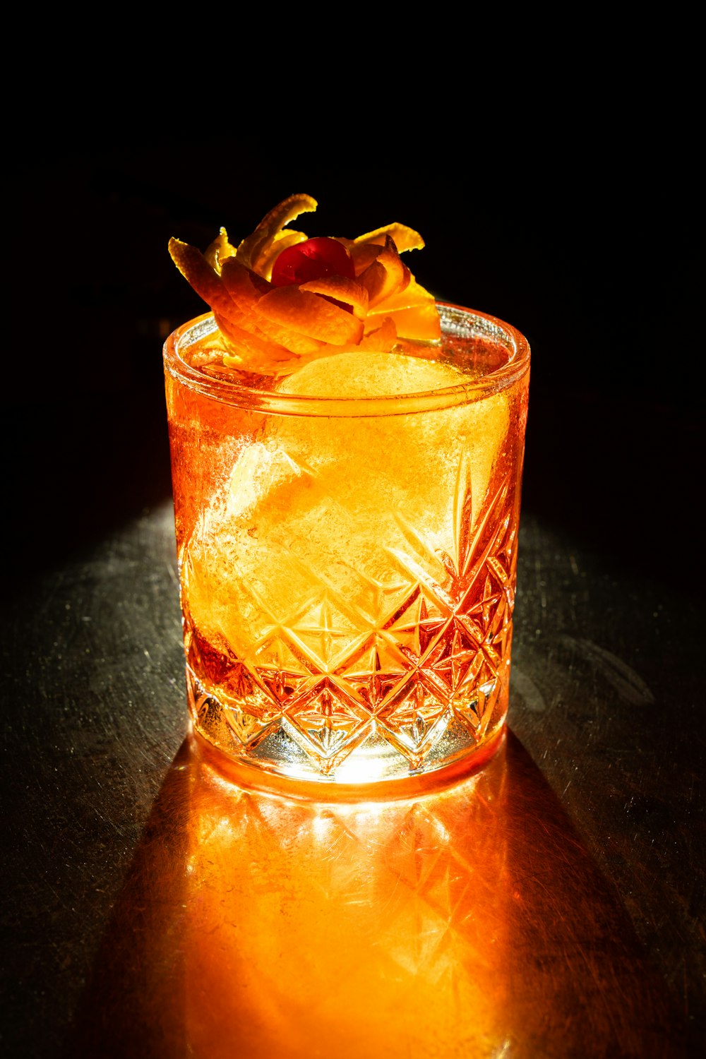 klares Trinkglas mit orangefarbener Flüssigkeit und Eis