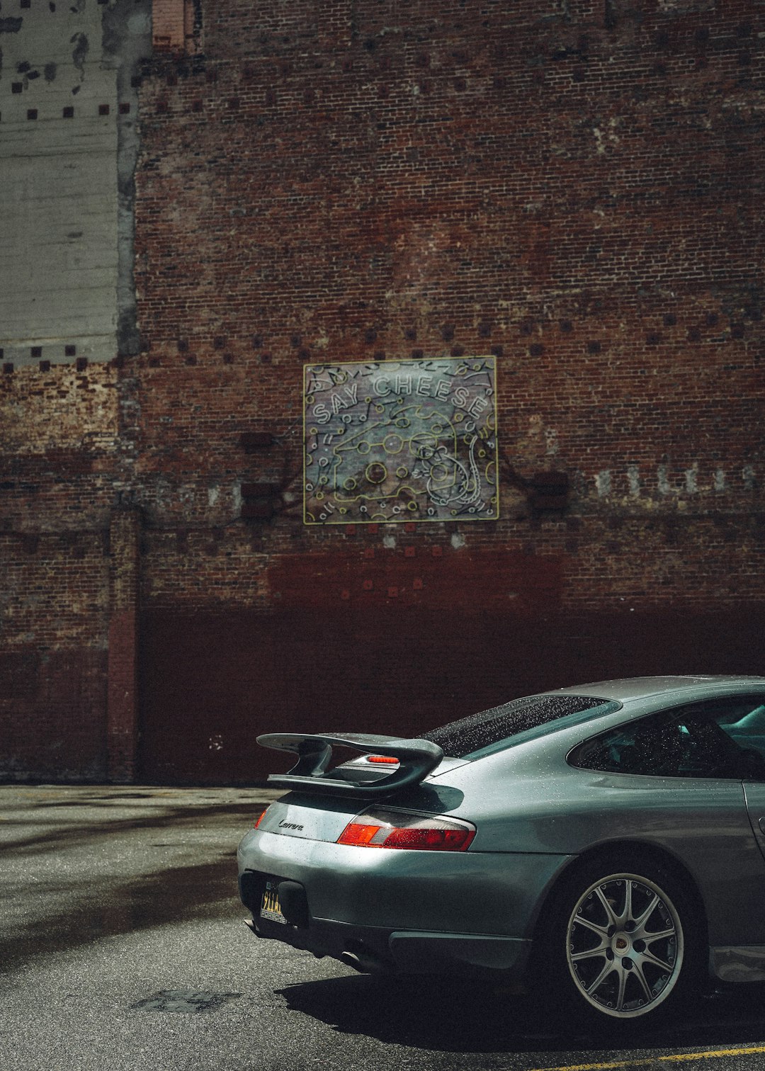 silver sedan parked beside brown brick wall