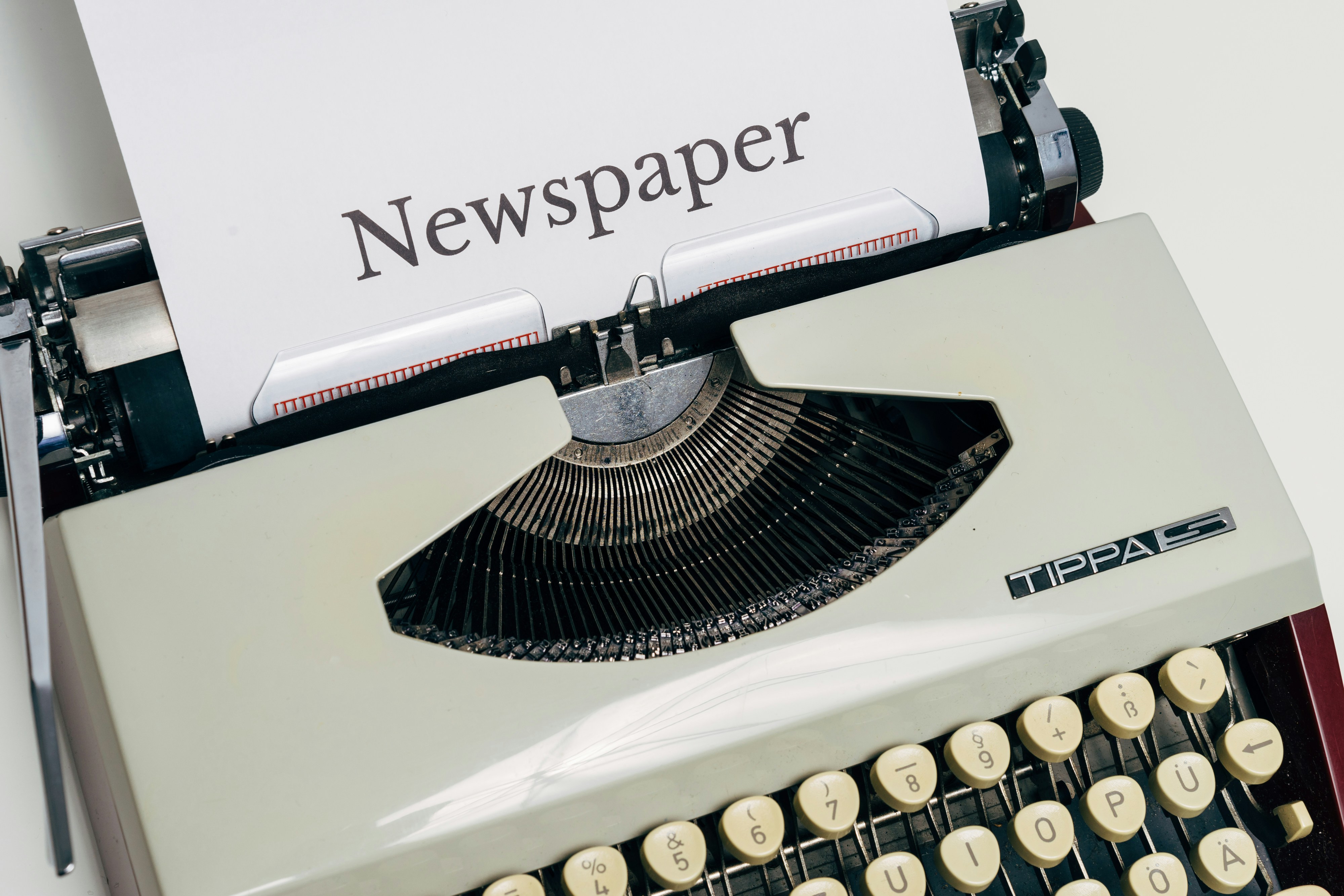 an old fashioned typewriter with a newspaper on top of it