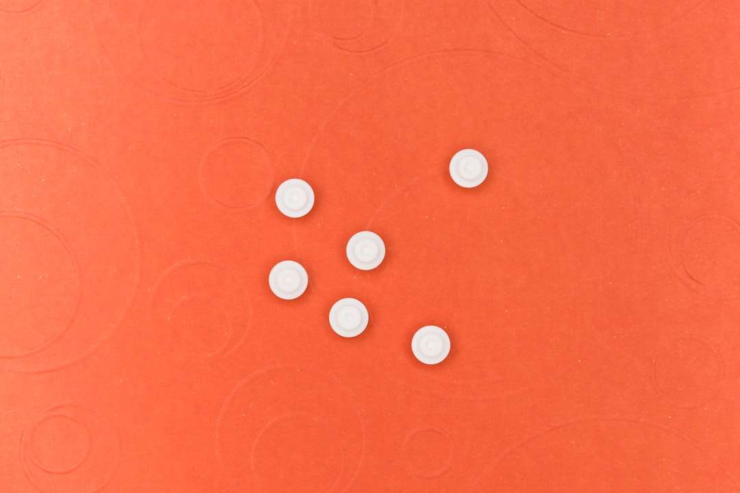 white round medication pill on red surface
