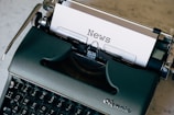 green and white typewriter on brown wooden table