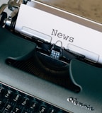 green and white typewriter on brown wooden table