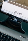 green and white typewriter on brown wooden table