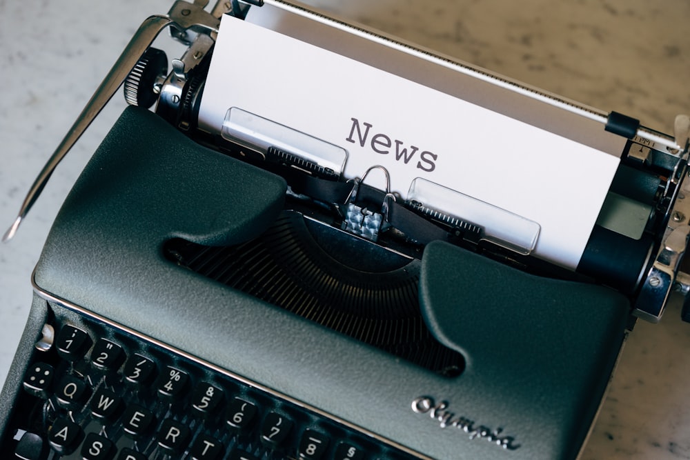 green and white typewriter on brown wooden table