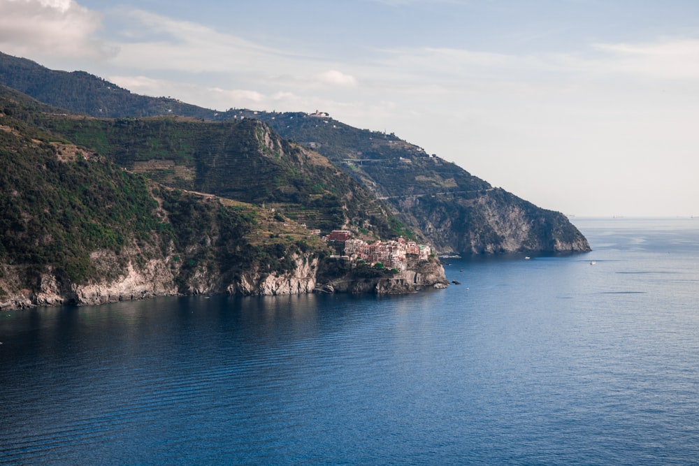 green and brown mountain beside blue sea under blue sky during daytime