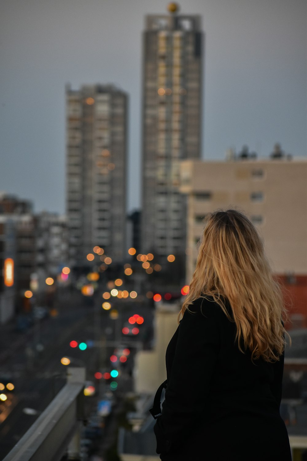 mulher no casaco preto em pé no topo do edifício durante o dia