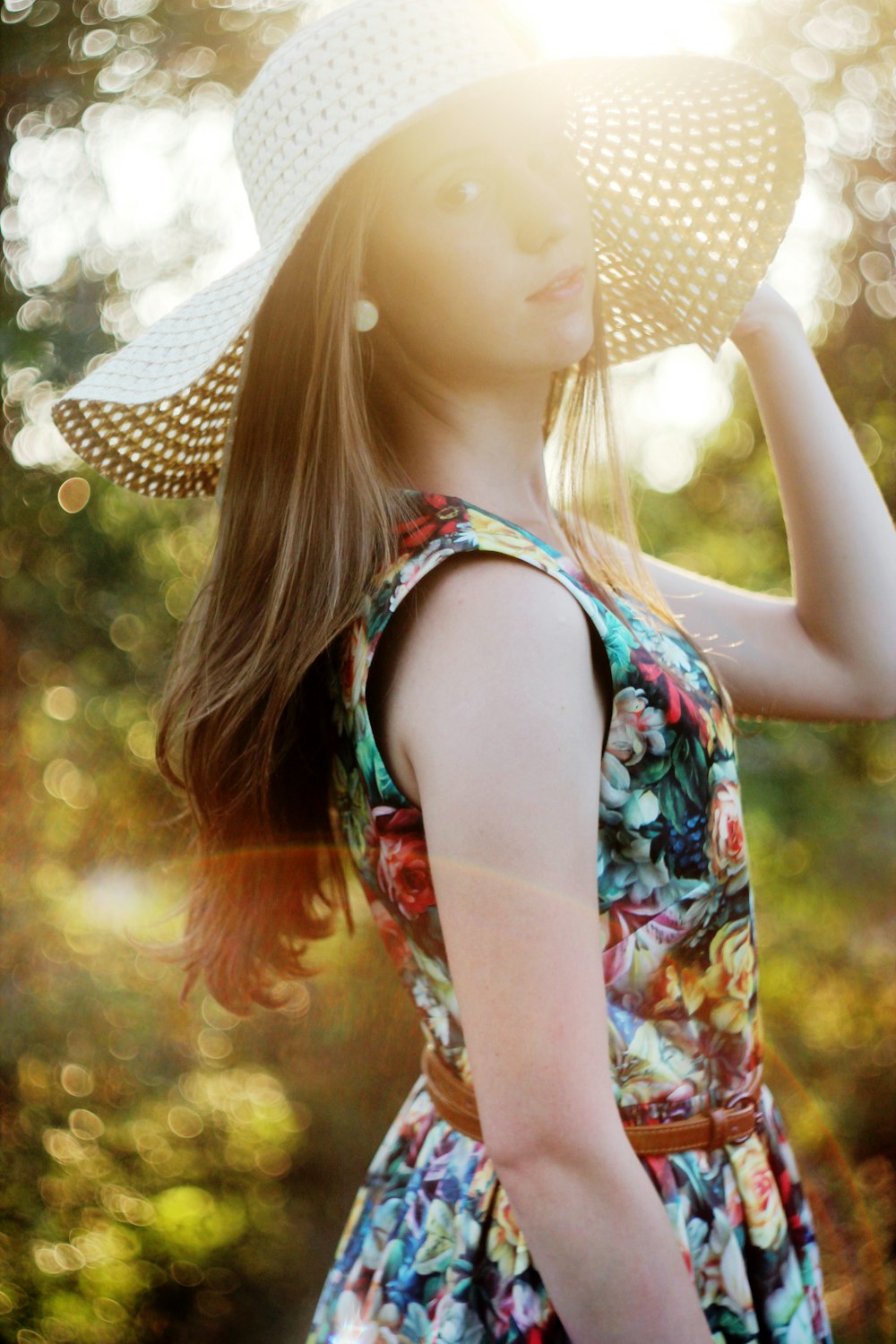 woman in white and blue floral tank top wearing white and black polka dot sun hat