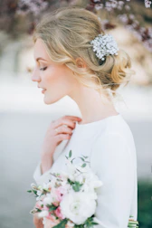 A bride smiling with an elegant updo adorned with delicate floral accents.