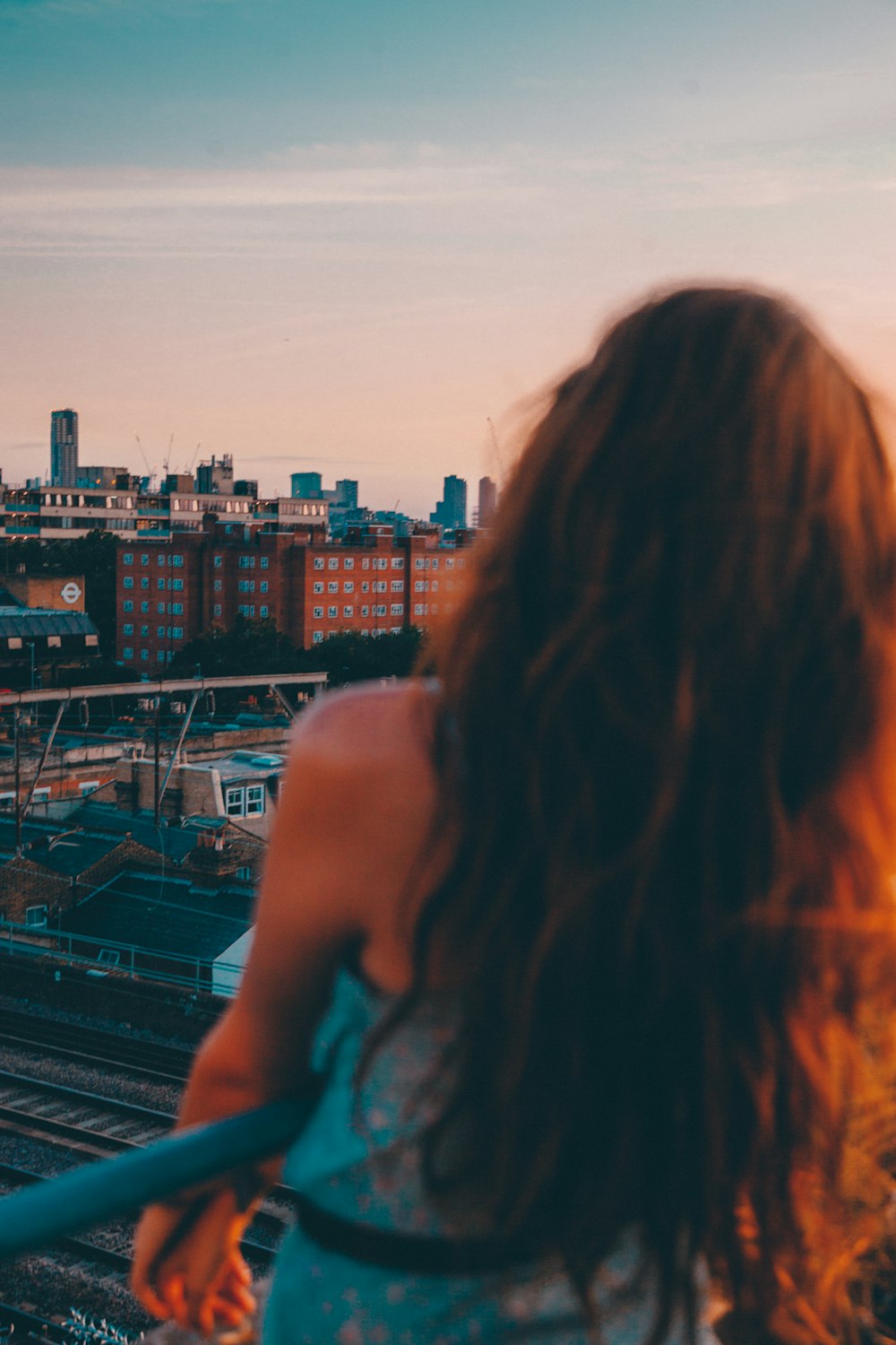 woman in teal tank top standing on top of building during daytime