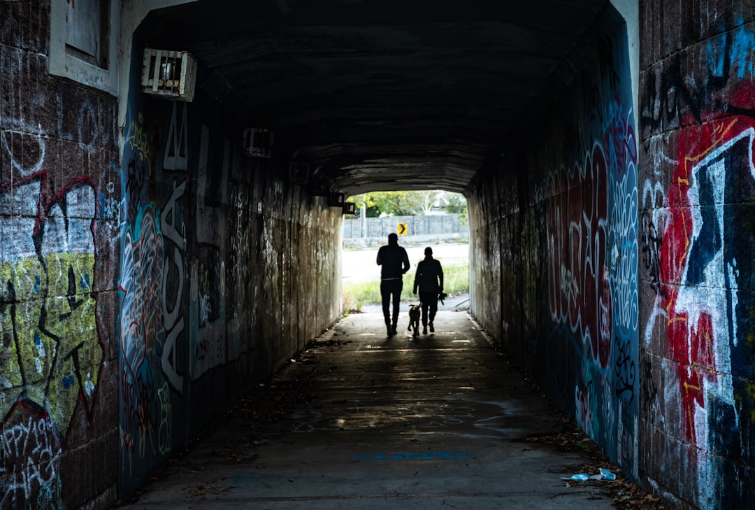 man in black jacket walking on tunnel