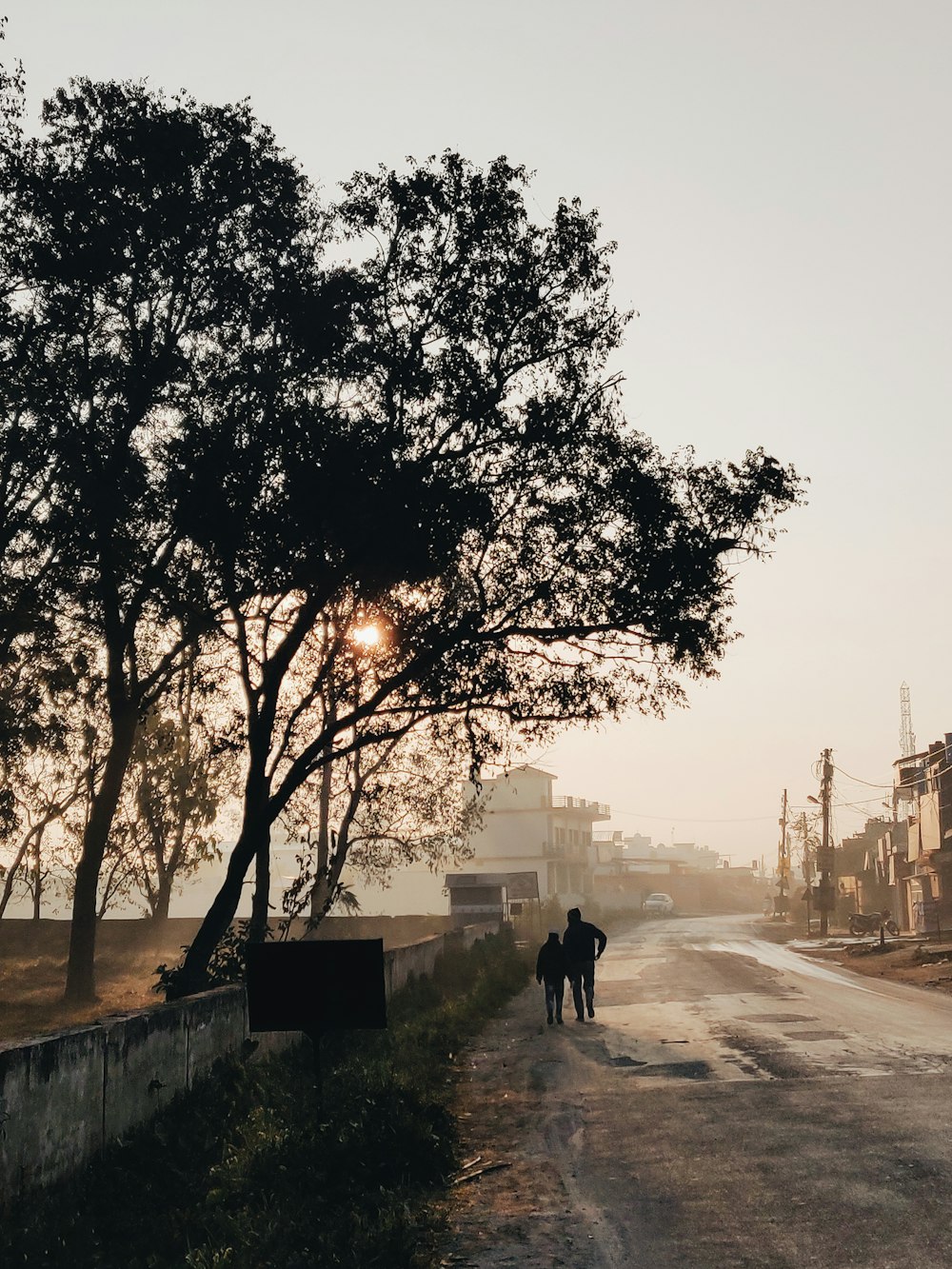 silhouette of man and woman walking on road during sunset