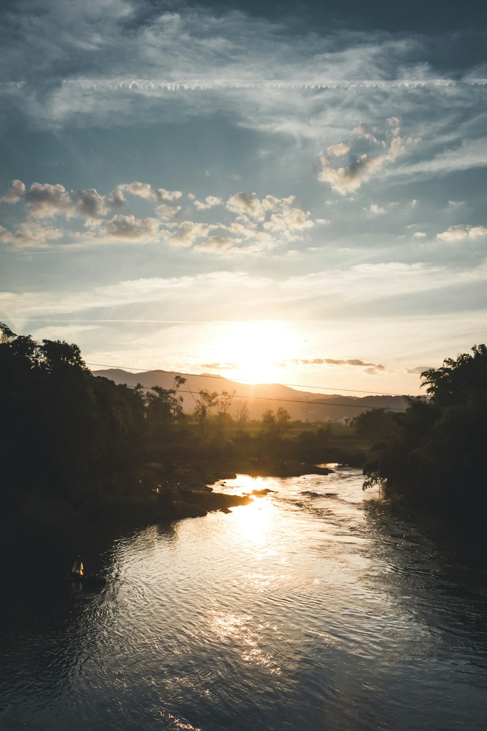 body of water between trees during sunset