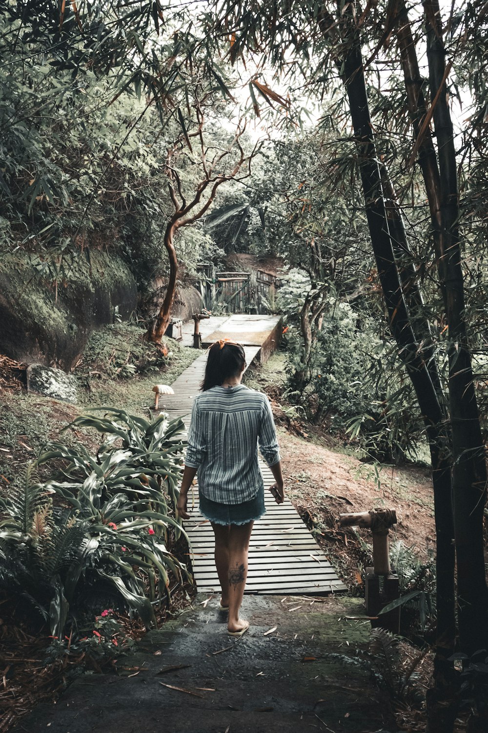 woman in blue denim jacket walking on wooden bridge