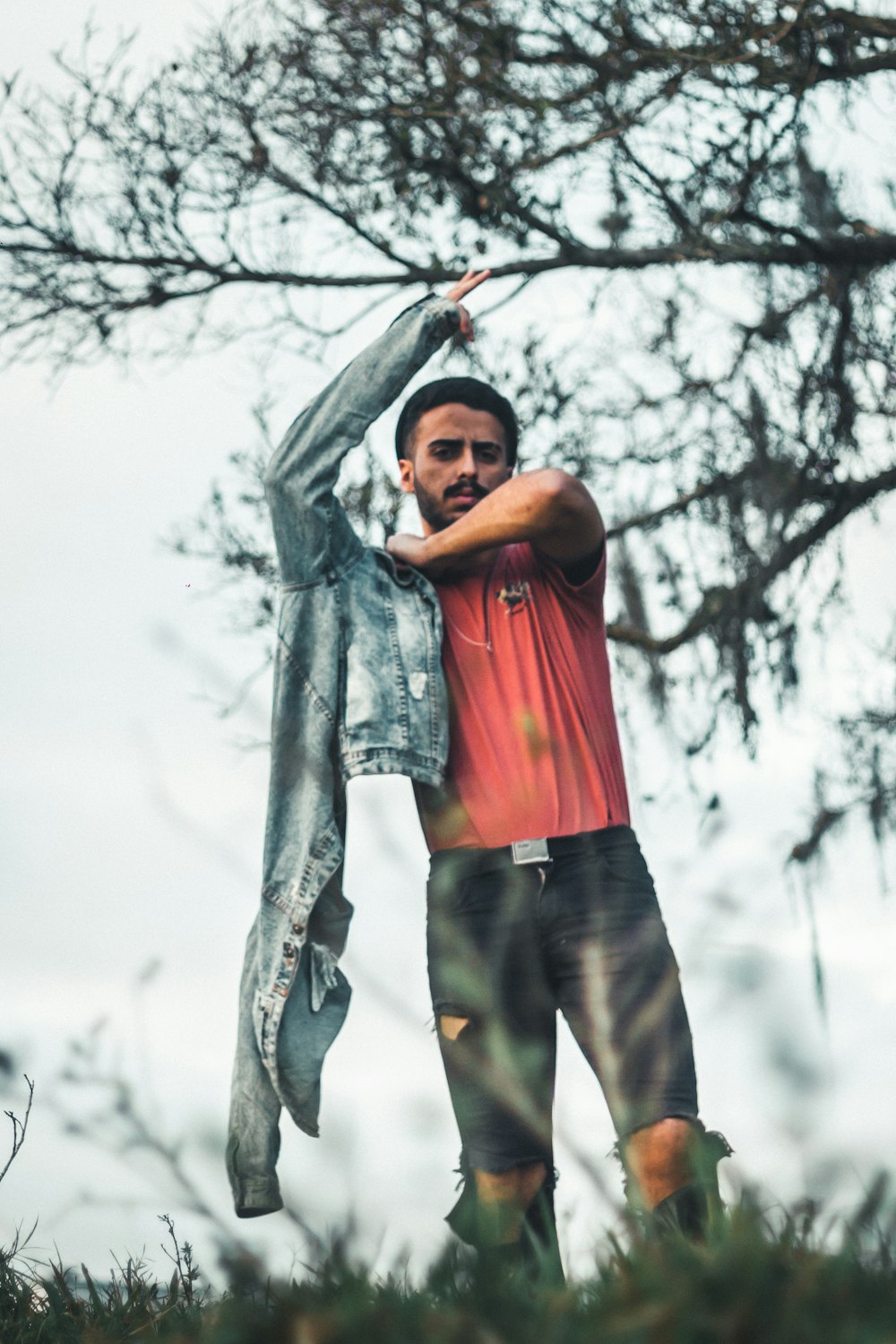 man in red shirt and black pants holding gray tree branch