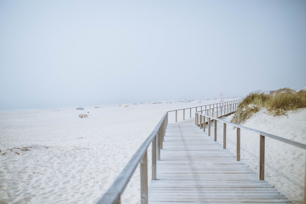 brown wooden bridge on white sand during daytime