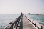person in black shirt walking on wooden dock during daytime
