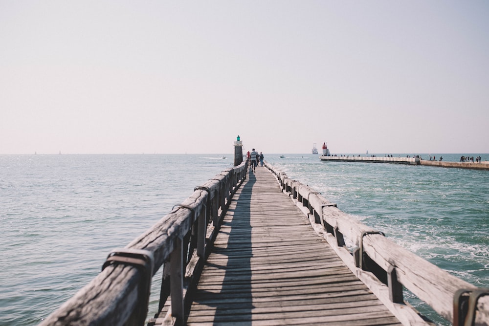 person in black shirt walking on wooden dock during daytime