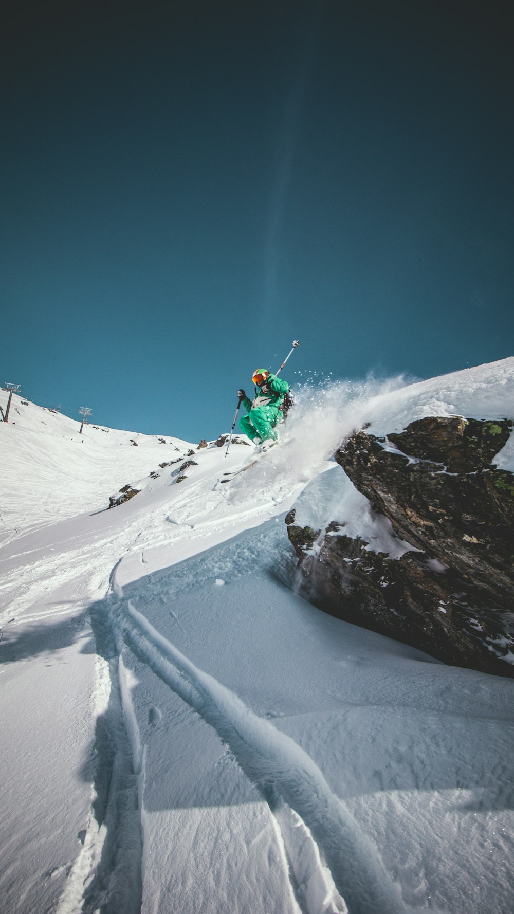 person in green jacket riding snowboard on snow covered mountain during daytime