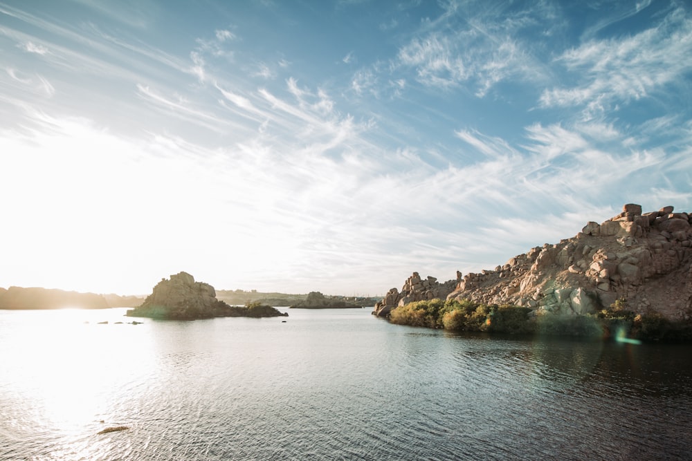 brown rock formation on body of water under blue sky during daytime