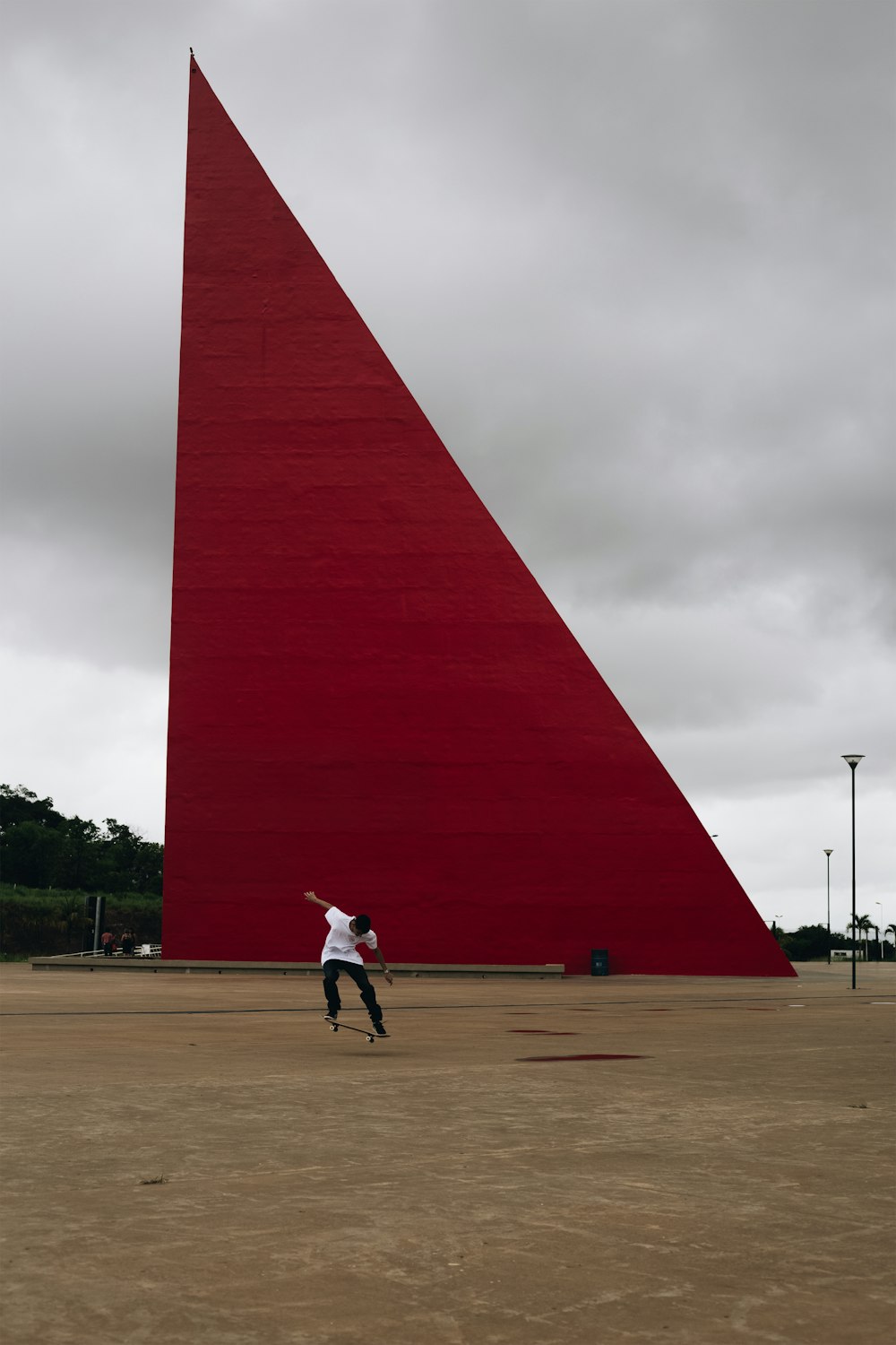 man in white shirt and black pants walking on brown field near red concrete building during