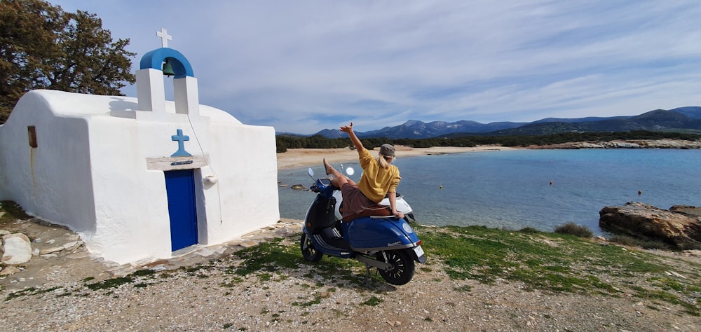 woman in brown jacket riding blue motor scooter on beach during daytime
