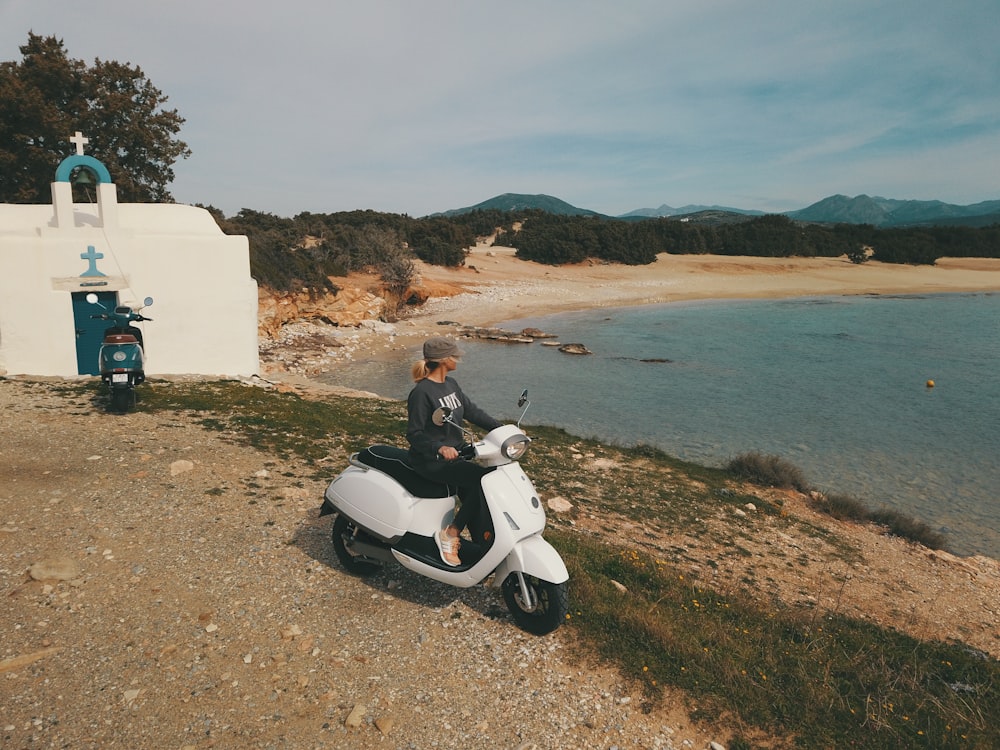 white and black motor scooter on green grass field near body of water during daytime