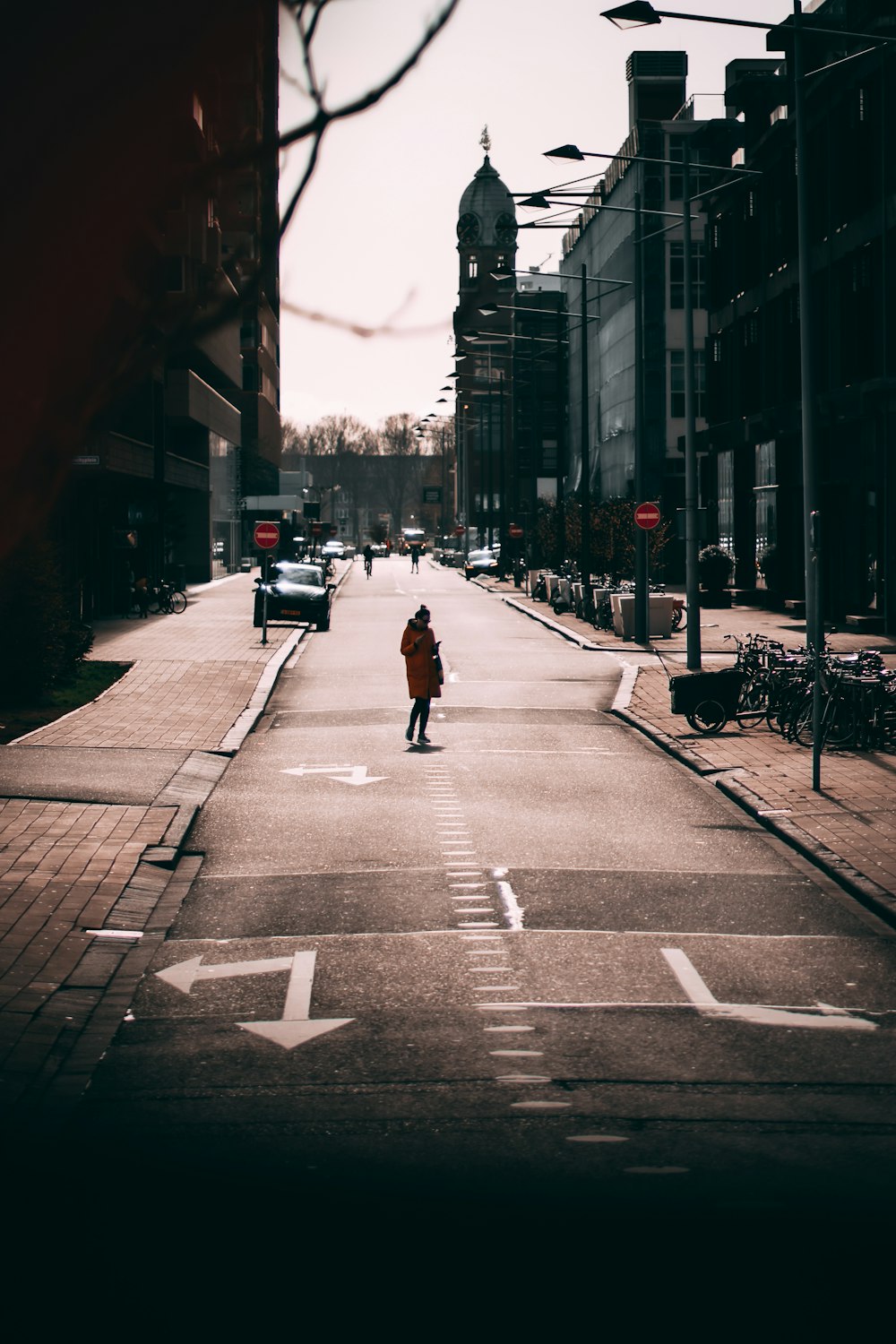 person in black jacket and black pants walking on pedestrian lane during daytime