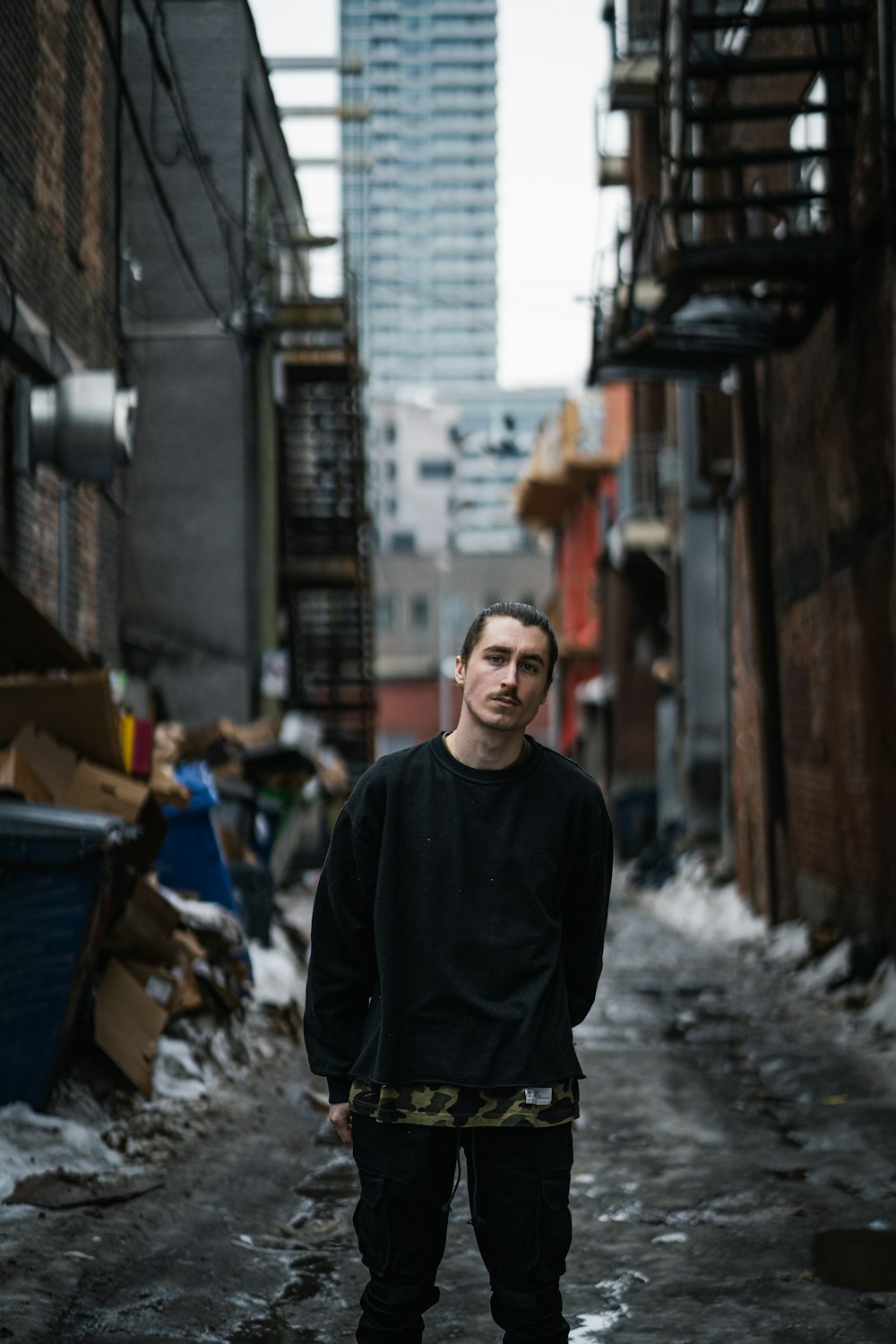 man in black crew neck shirt standing on street during daytime