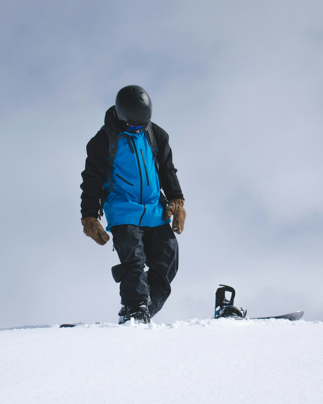 man in blue jacket and black pants standing on snow covered ground ...