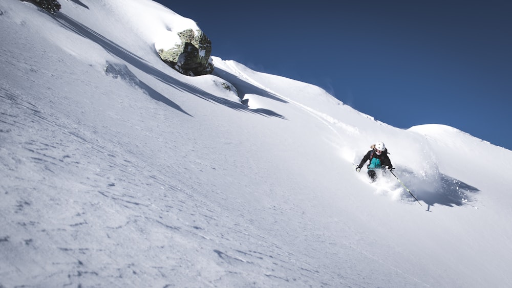 person riding snow ski on snow covered ground during daytime