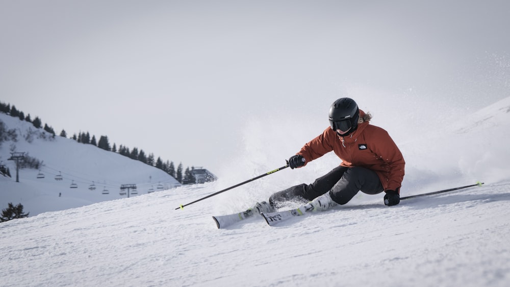 person in red jacket and black pants riding on snow board during daytime