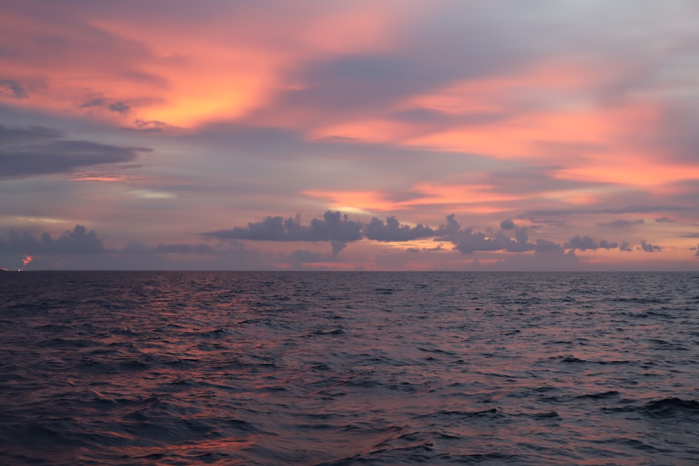 body of water under cloudy sky during sunset