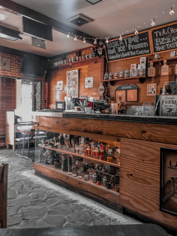 Cozy coffee shop interior with warm lighting and wooden tables filled with coffee cups and beans.